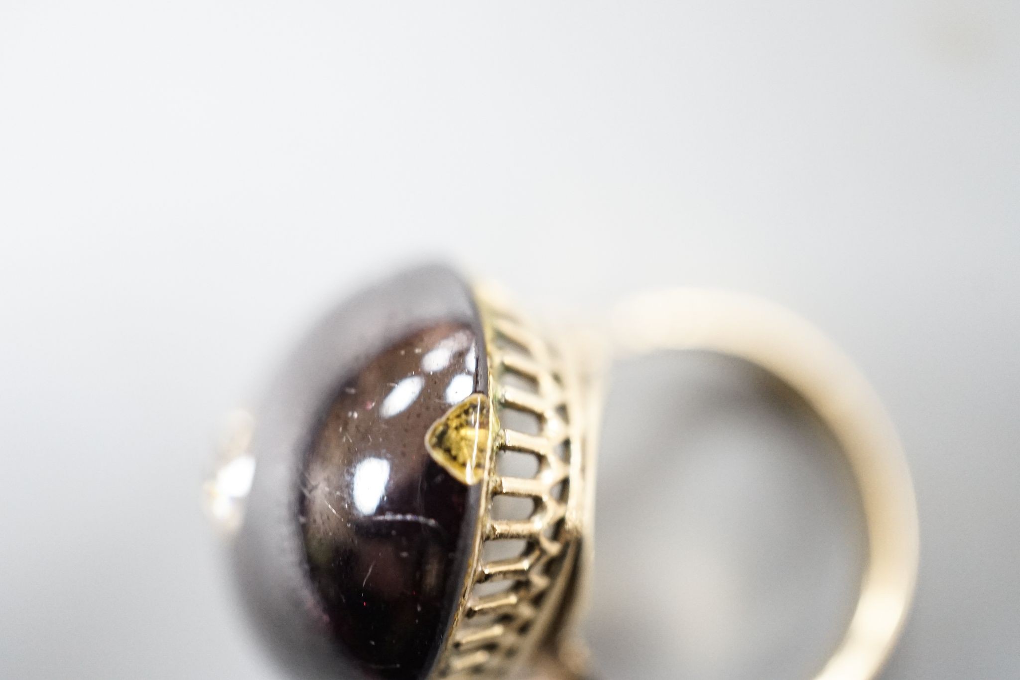 A yellow metal, foil backed cabochon garnet and diamond set oval dress ring, size P/Q, gross 11.1 grams, (a.f.).